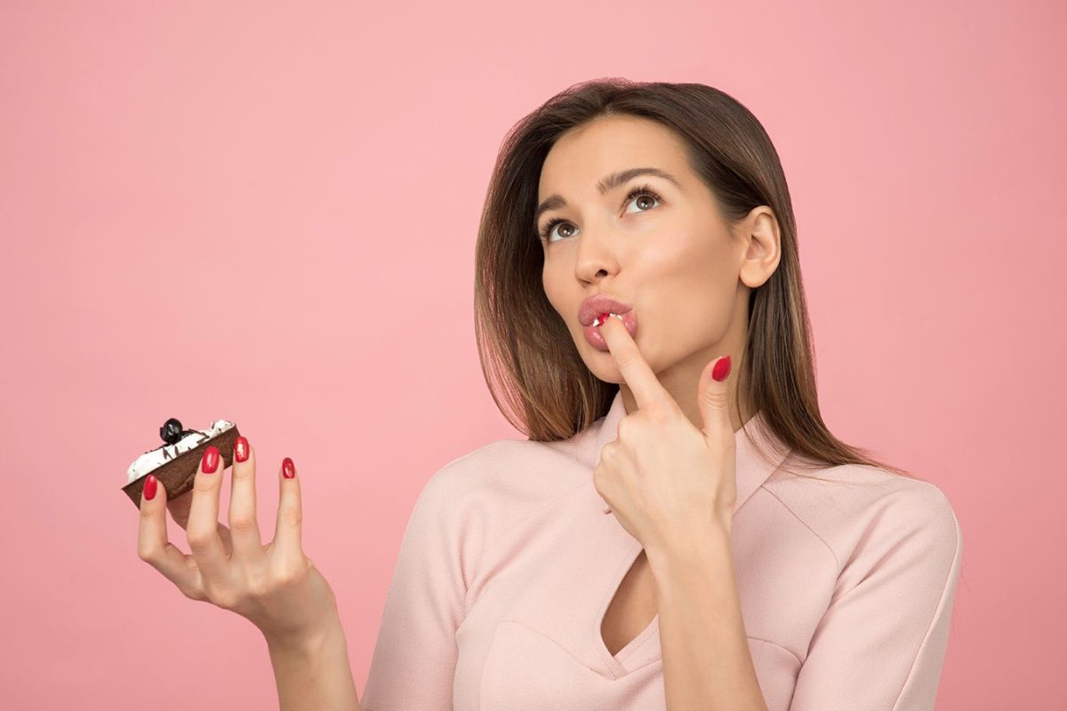 woman-eating-cupcake-while-standing-near-pink-background-1036621 woman-eating-cupcake-while-standing-near-pink-background-1036621